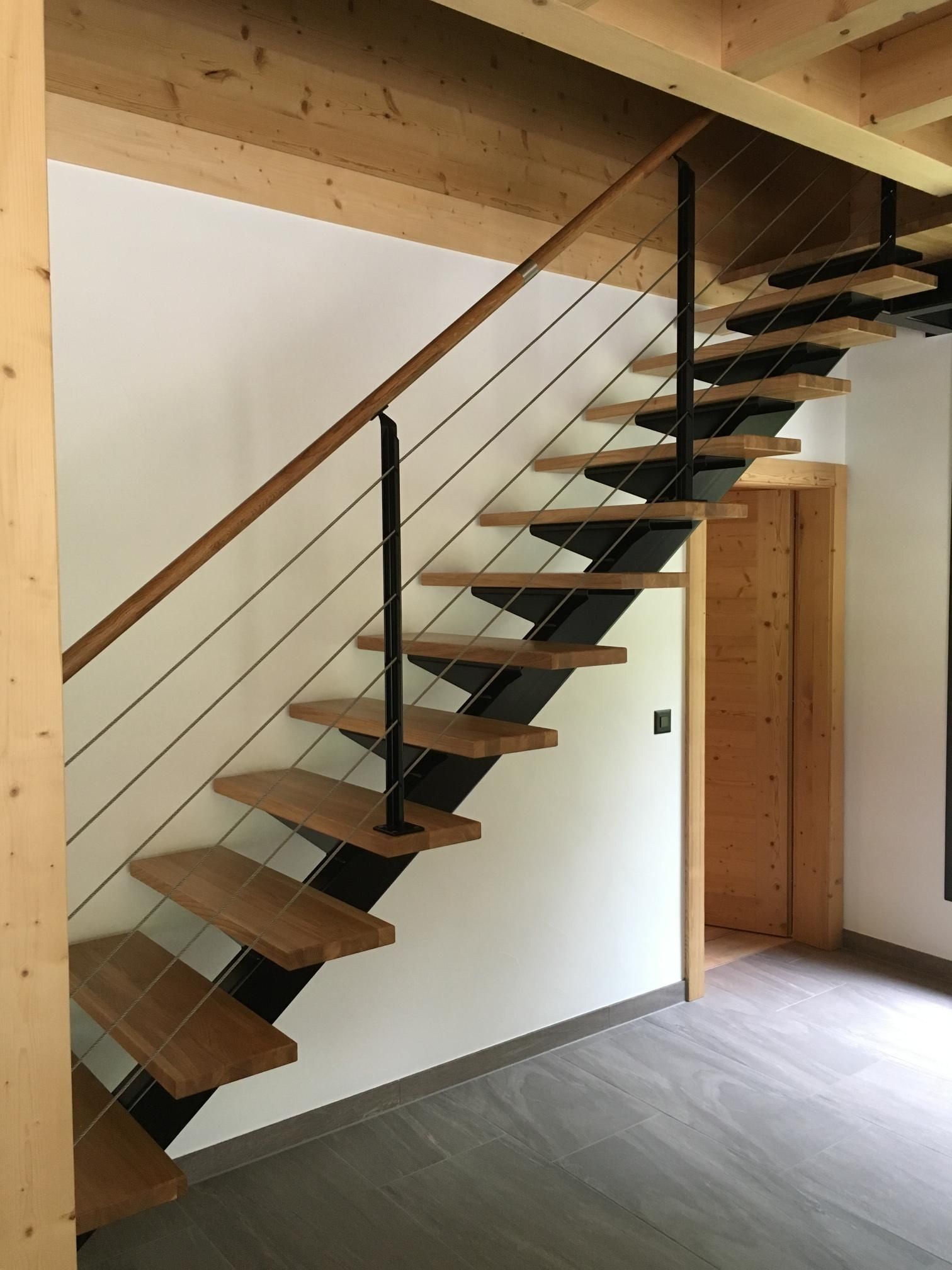 Un escalier en bois avec une rampe en métal.