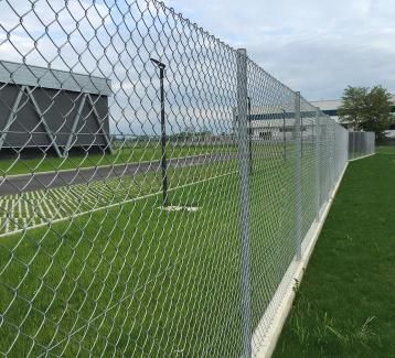 Une clôture à mailles de chaîne entoure un terrain de football.