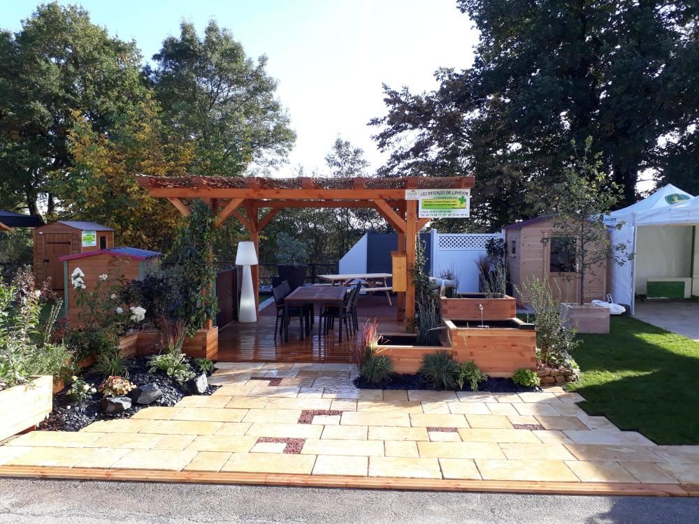 Patio arrière avec pergola en bois, table et chaises, allée pavée et massifs paysagers.