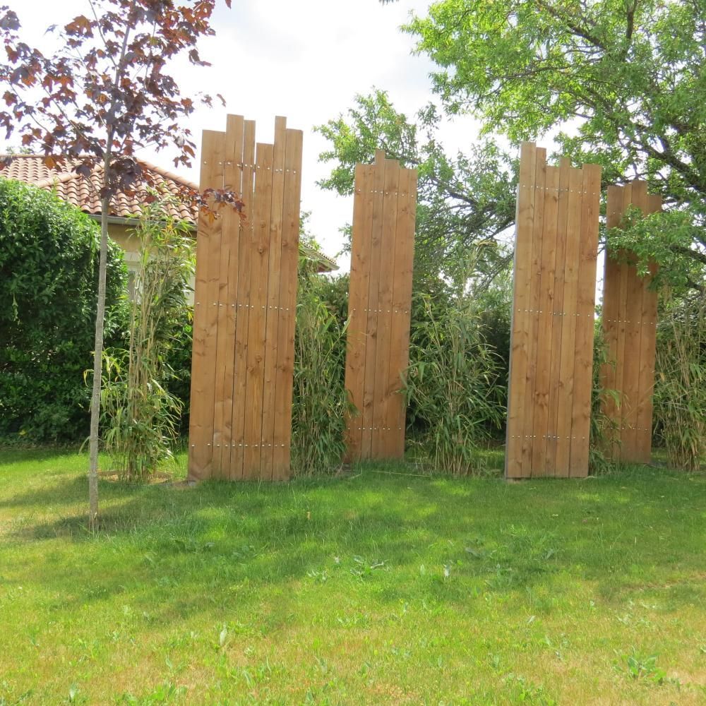Panneaux de clôture en bois dans un jardin herbeux, avec des arbres en arrière-plan
