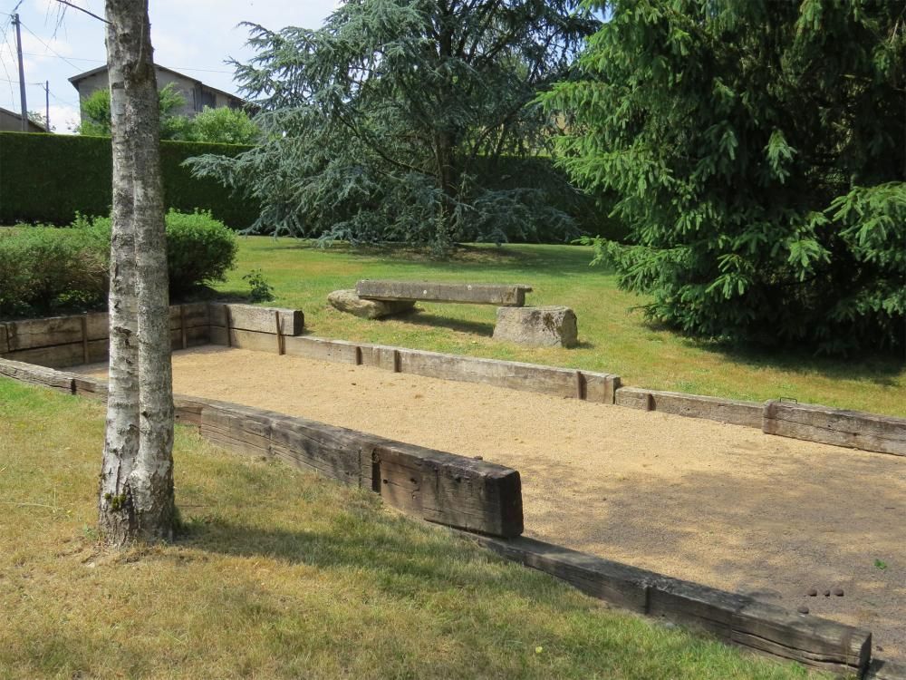 Parc ensoleillé avec une allée en gravier, des bancs et des arbres bordant une pelouse.