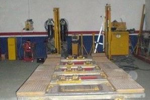 Montaje de pruebas industriales con una gran plataforma, maquinaria amarilla y equipos en un taller.