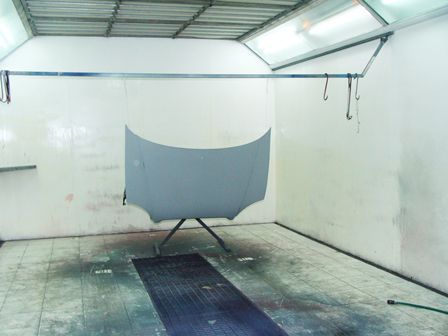 Habitación interior vacía con un panel de tela gris sobre un soporte y el suelo mojado debajo.
