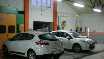 Dos coches blancos aparcados en el interior de un garaje o taller.