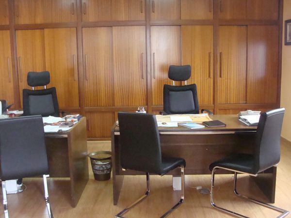 Oficina vacía con paredes revestidas de paneles de madera y dos escritorios enfrentados.