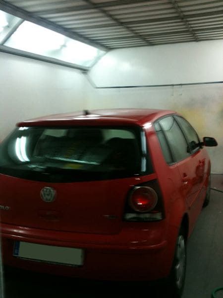 Volkswagen hatchback rojo estacionado en un garaje blanco.