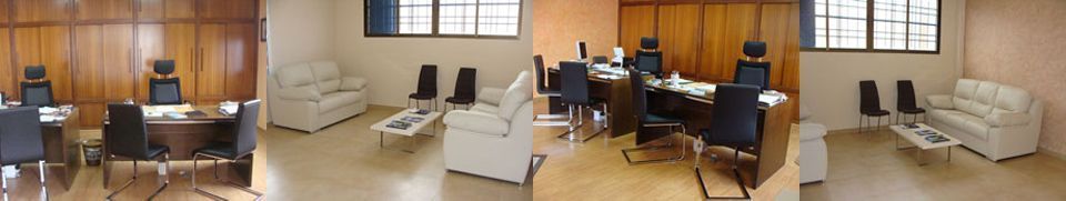 Sala de espera con paredes beige, sillas negras y sofás blancos; algunas personas sentadas en una habitación austera.