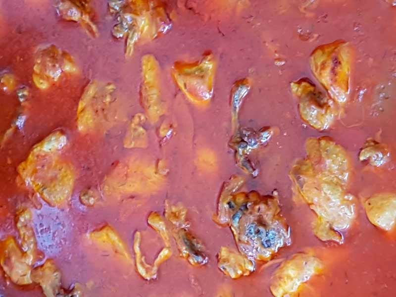 Un primer plano de una salsa roja con carne.