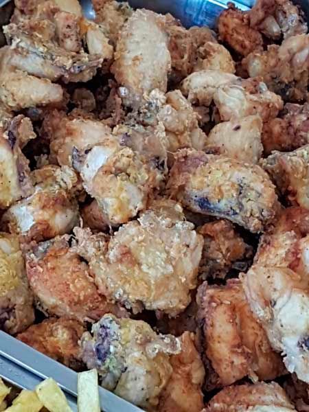 Una bandeja de pollo frito y papas fritas en una mesa.