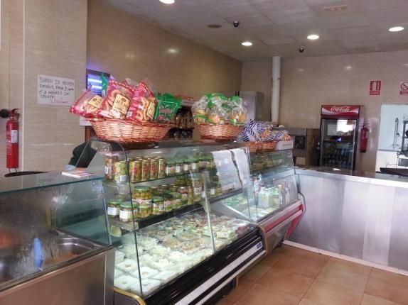 El interior de una panadería con una vitrina de cristal llena de comida.