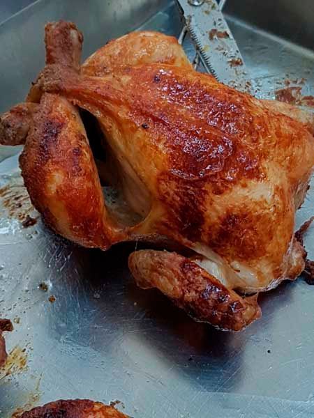 Un pollo asado está sentado encima de una sartén de metal.