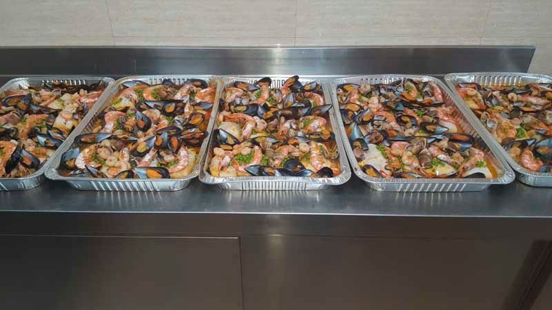 Hay tres bandejas de comida sobre un mostrador de acero inoxidable.