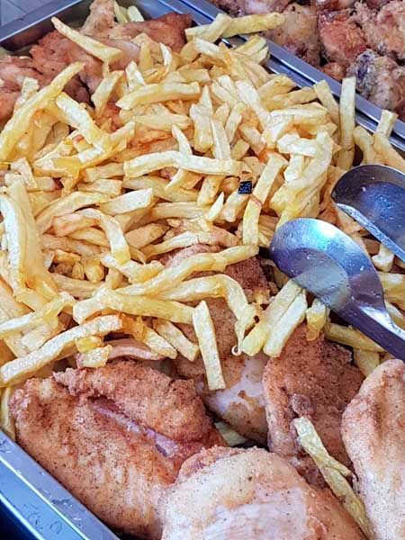 Un primer plano de una bandeja de comida con papas fritas y pollo.