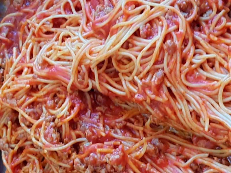 Un primer plano de espaguetis con salsa de tomate y carne.