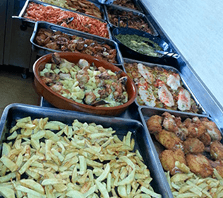 Un buffet lleno de una variedad de alimentos, incluidas papas fritas.