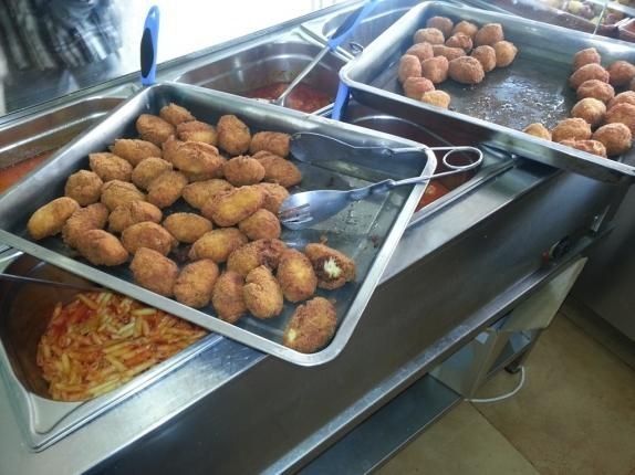 Hay varias bandejas de comida en un mostrador de un restaurante.