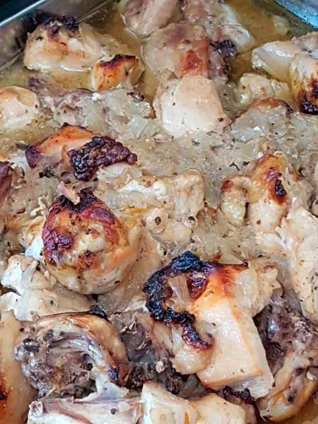 Un primer plano de una cazuela llena de pollo y cebollas.