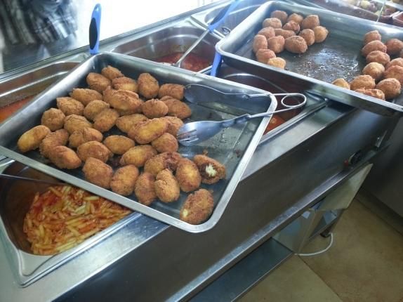 Hay varias bandejas de comida en un mostrador de una cocina.