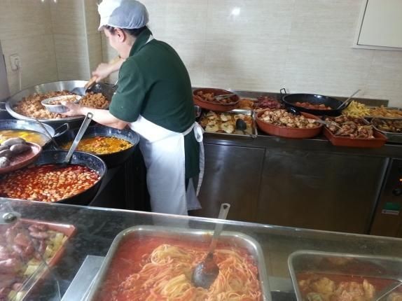 Un hombre con una camisa verde está preparando comida en una cocina.