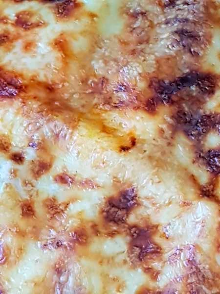 Un primer plano de una pizza con mucho queso encima.