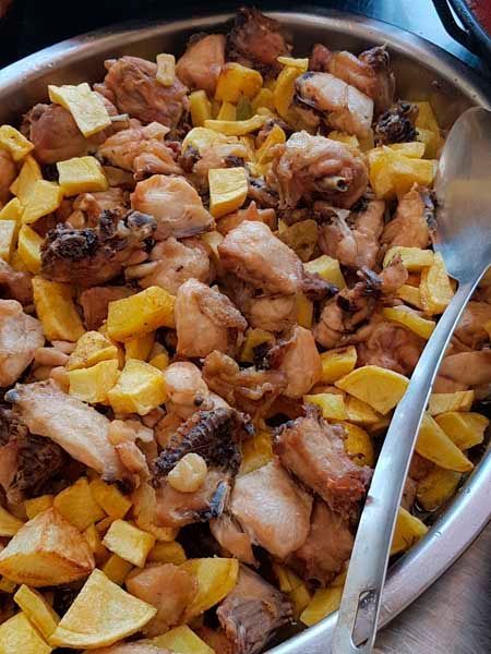 Un tazón de pollo y patatas con una cuchara dentro.