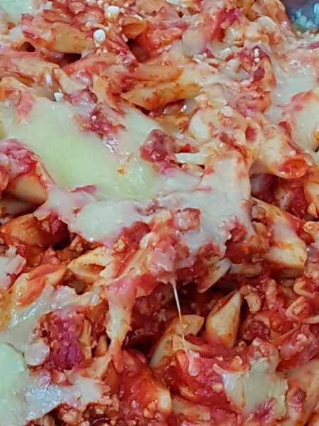 Un primer plano de un plato de pasta con salsa de tomate y queso.