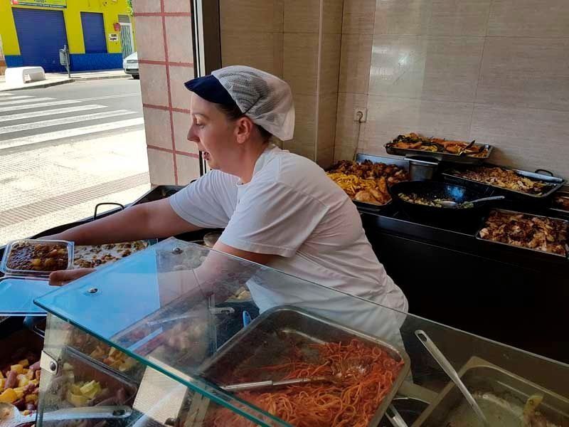 Una mujer con un delantal blanco está trabajando en un restaurante.