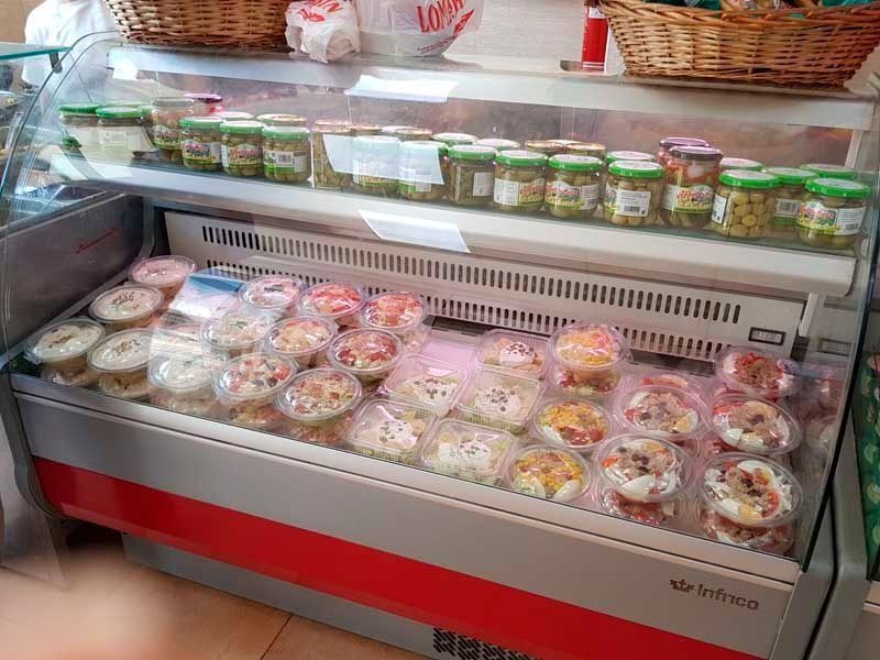 Un refrigerador lleno de frascos de comida en una tienda.