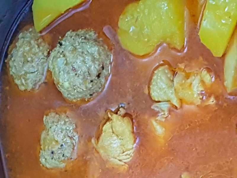 Un primer plano de un tazón de sopa con albóndigas y patatas.