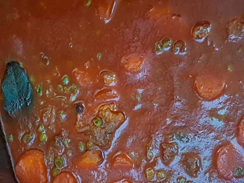 Un primer plano de una olla de guisado con zanahorias y guisantes.