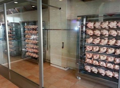 Una habitación con muchos pollos en rejillas.