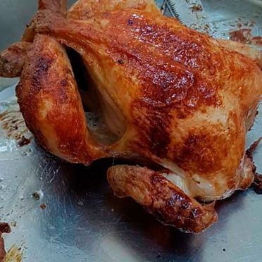 Un pollo asado está sentado encima de una sartén de metal.