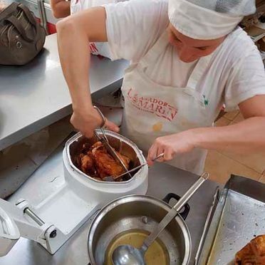 Una mujer está cocinando pollo en una freidora en una cocina.