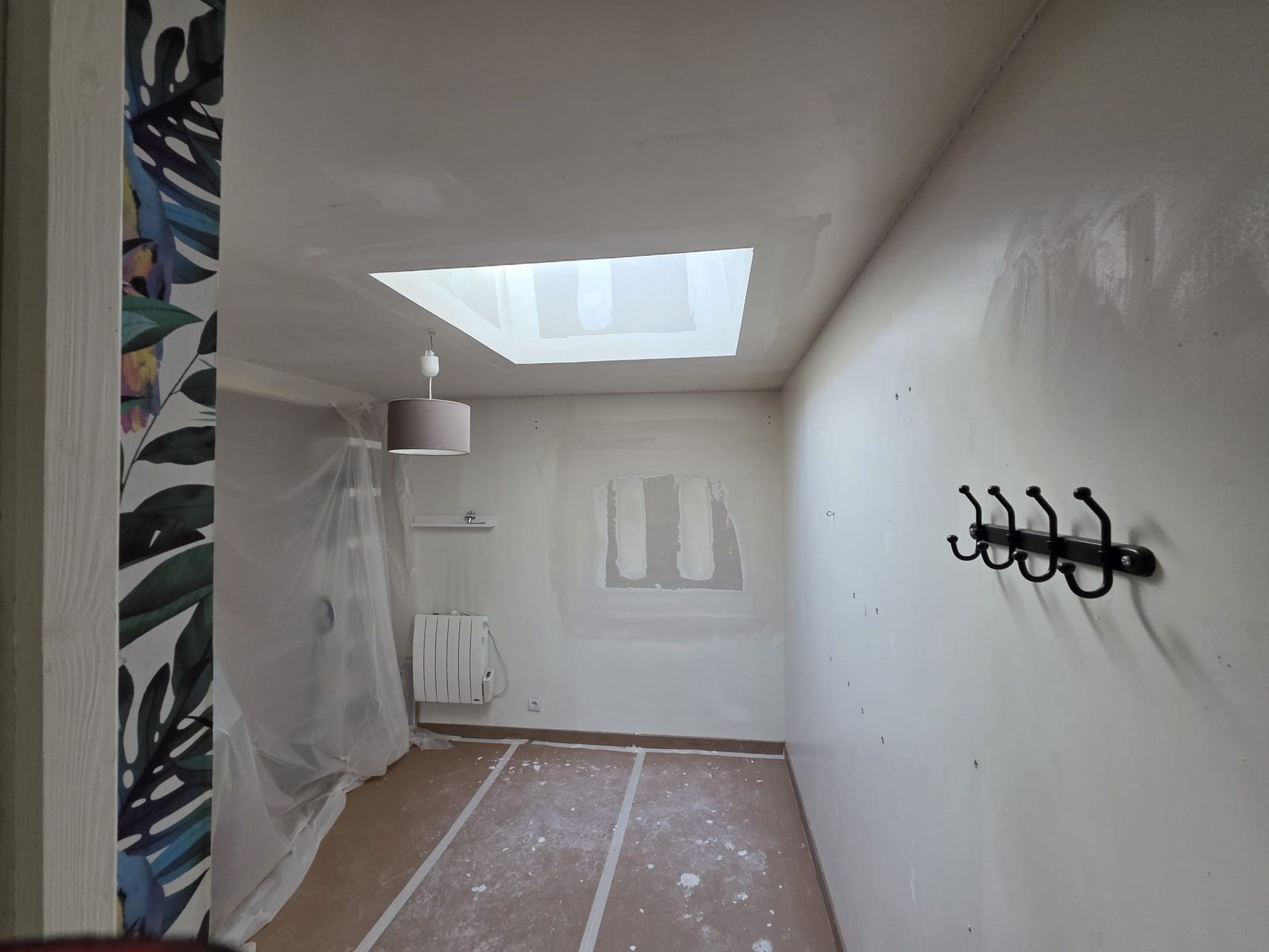 Rénovation de la pièce : une moitié en béton brut, l’autre moitié finie avec des lattes de bois, un mur en marbre et un parquet.
