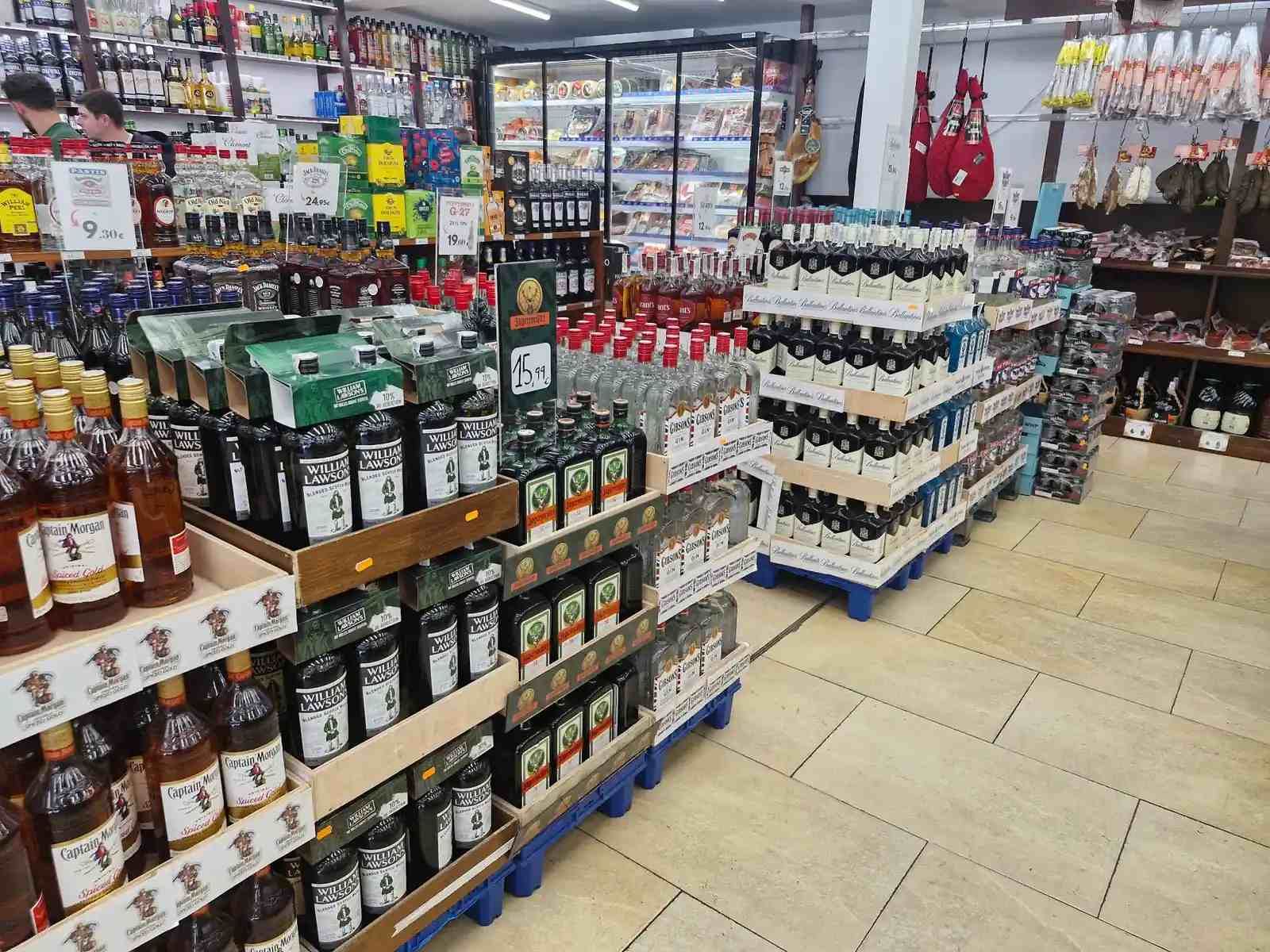 Interior de una licorería con estantes repletos de diversas botellas de alcohol.