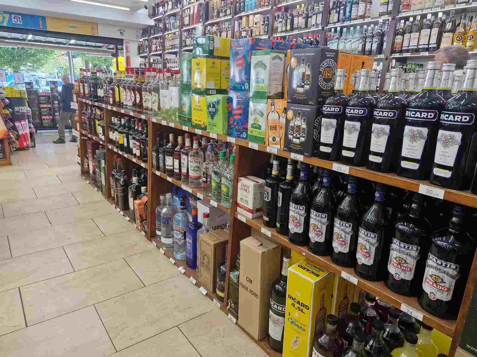 Interior de una licorería con estantes repletos de diversas botellas de alcohol.
