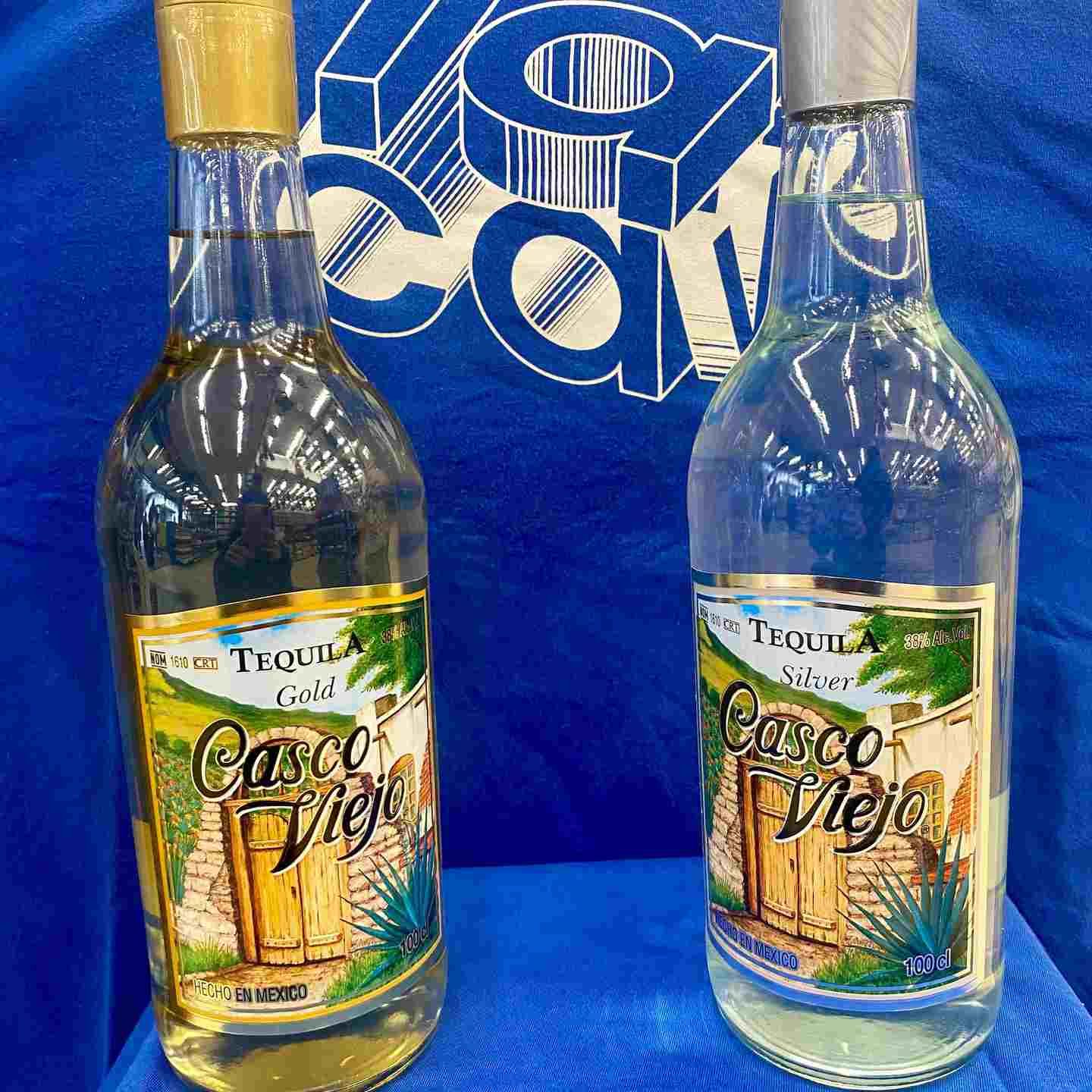 Dos botellas de tequila Casco Viejo, una dorada y otra plateada, sobre un fondo azul.