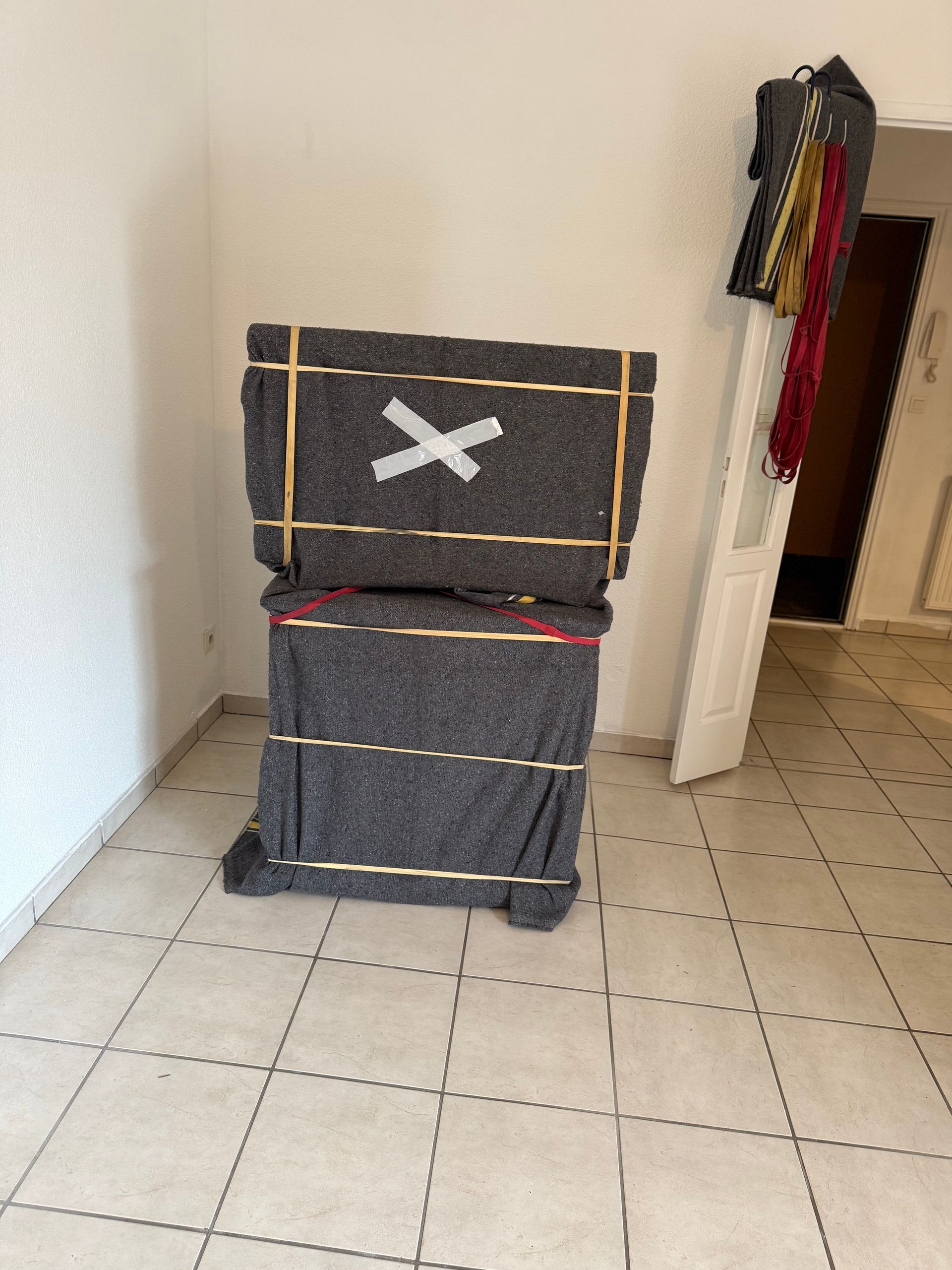 Deux boîtes enveloppées dans du tissu gris, fermées par des bandes dorées et marquées d'un X blanc