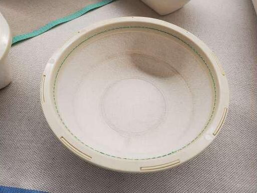 Un recipiente blanco con una raya verde está sobre una mesa.