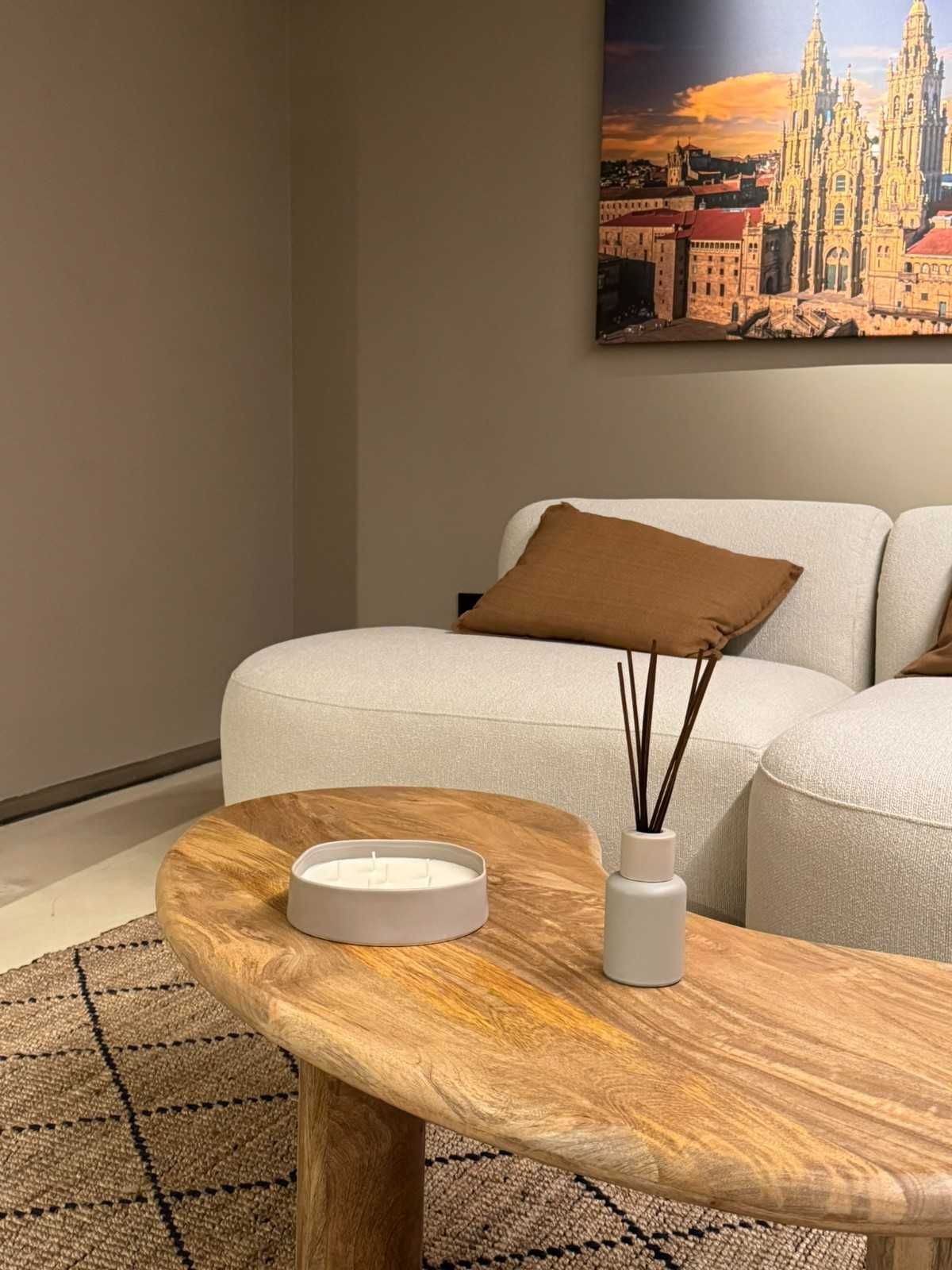 Sala de estar con sofá beige, cojines marrones, mesa de centro de madera y arte.