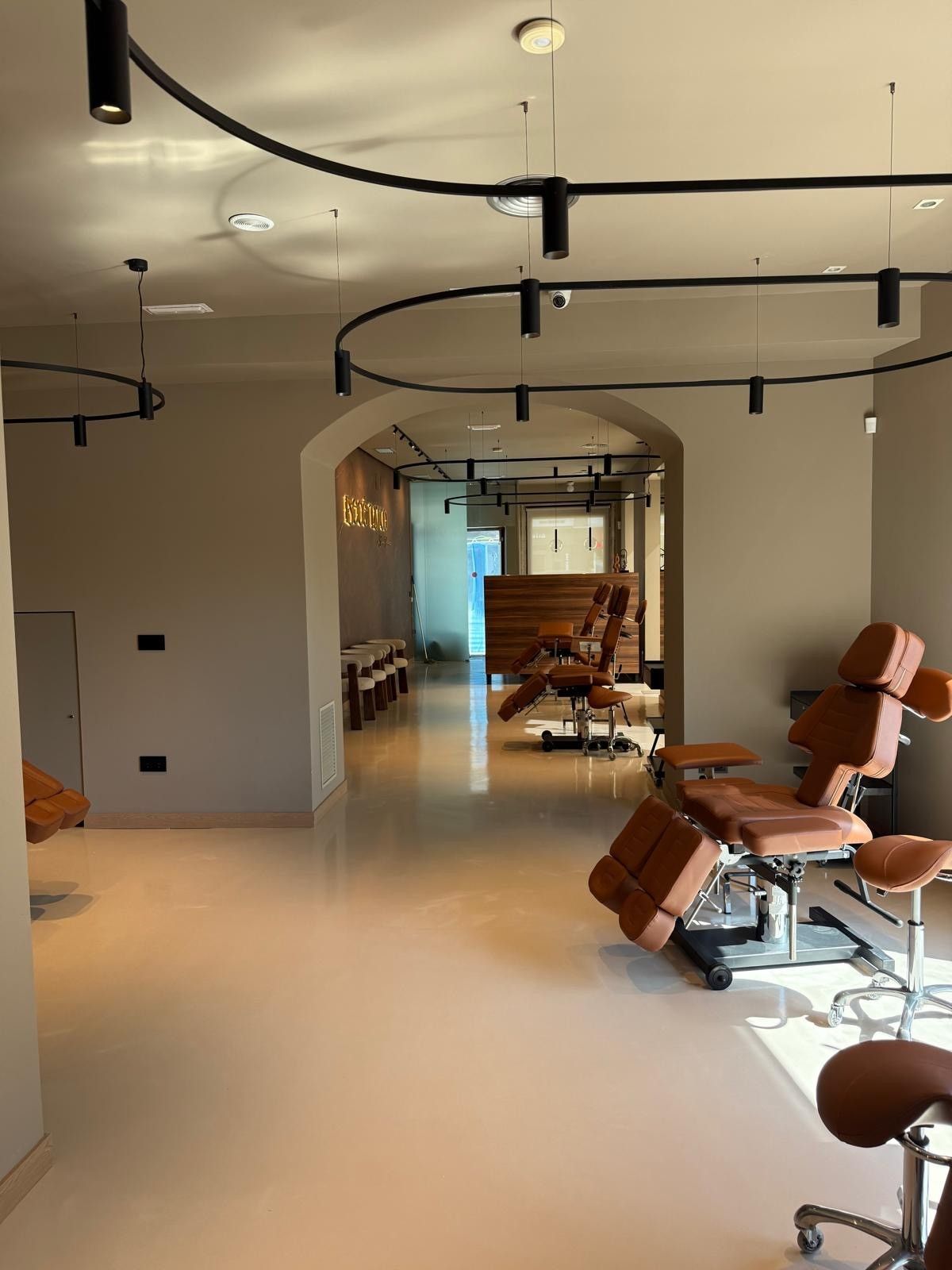 Interior de una clínica moderna con paredes de color canela, piso de color claro y sillas de tratamiento marrones.