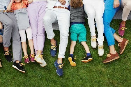 Menschen in bunten Hosen und Schuhen liegen im Gras.