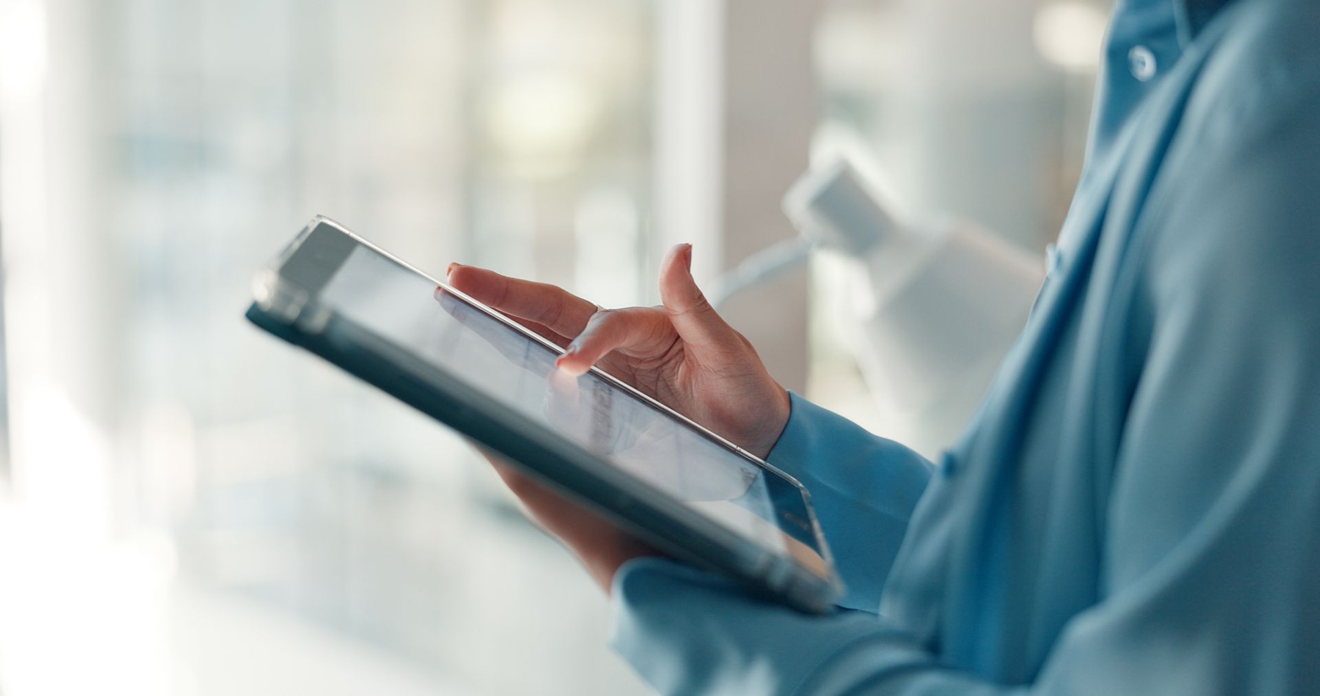 Une personne utilisant une tablette avec un stylet dans un environnement de bureau lumineux.