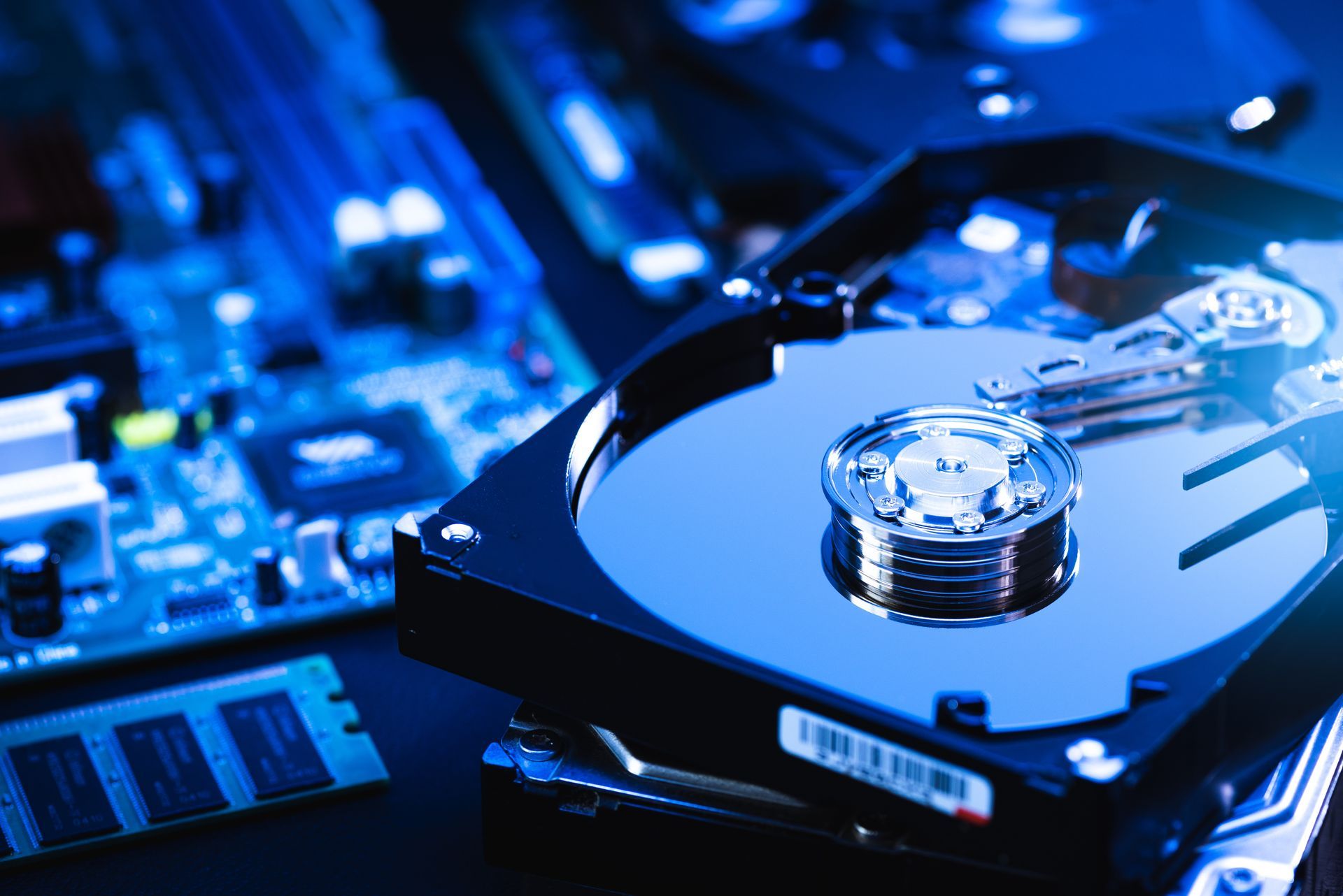 Gros plan sur un disque dur brillant sur une carte mère d'ordinateur éclairée en bleu.