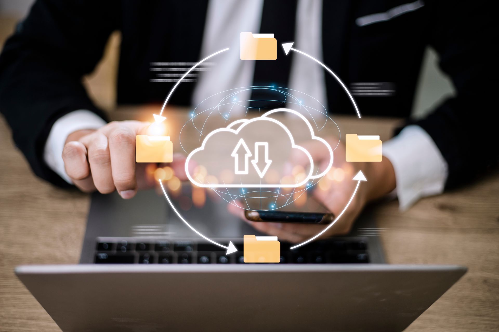 Des mains tenant une icône lumineuse de téléchargement/téléversement dans un nuage au-dessus d'un ordinateur portable, entourée d'icônes de dossiers connectés.