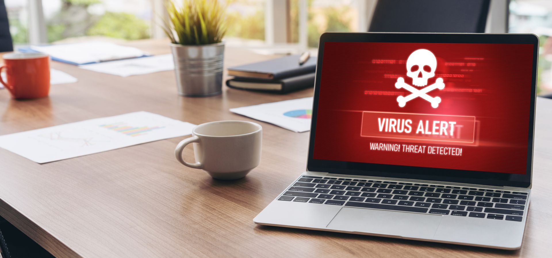 Ordinateur portable sur le bureau affichant un écran d'alerte de virus rouge (une tête de mort).