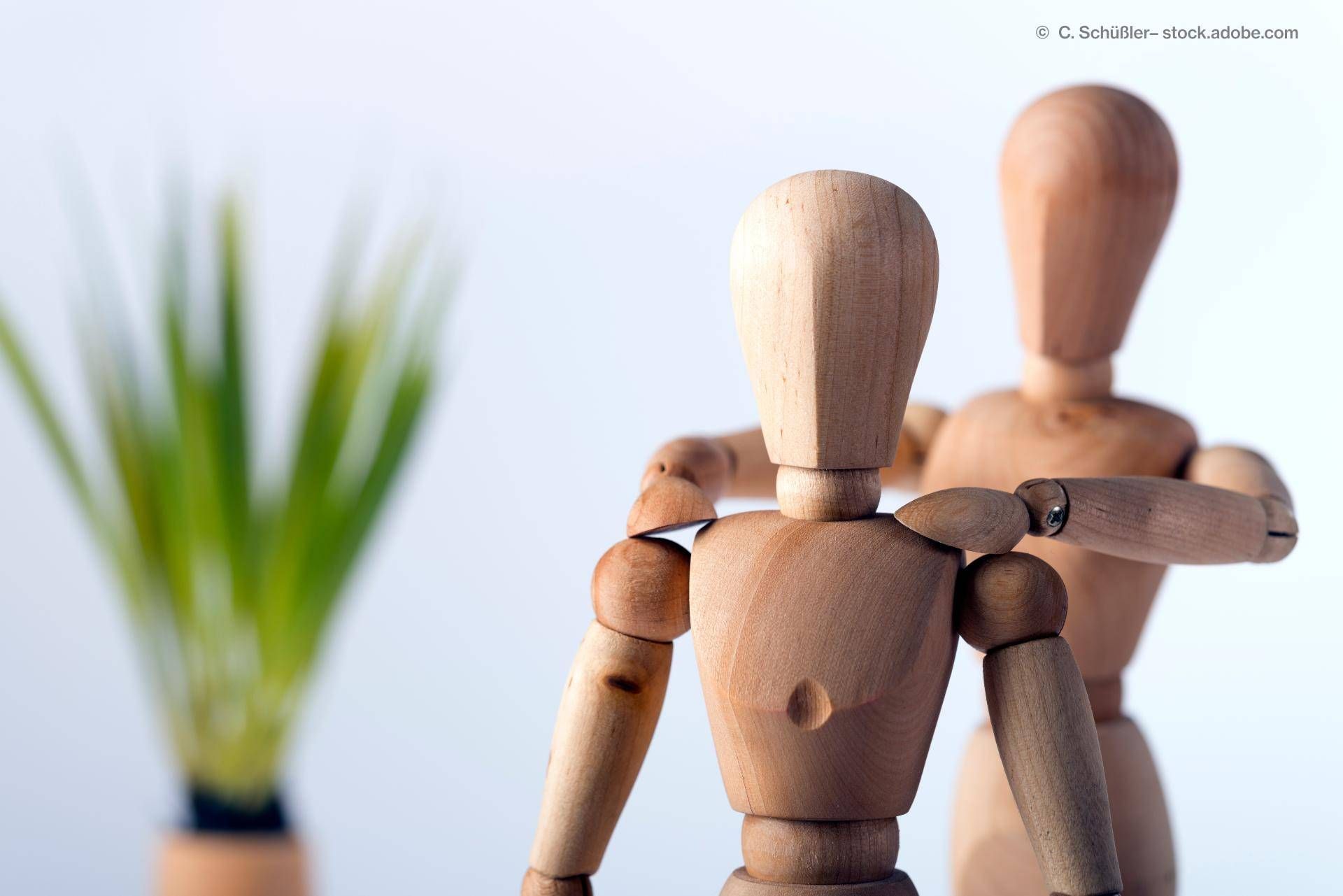 Eine Figur hat die Hände auf den Schultern der anderen