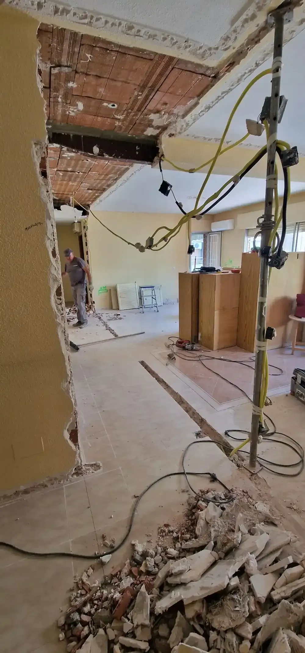 Interior de una habitación en construcción, con dos ventanas, paredes de cemento y herramientas de construcción.
