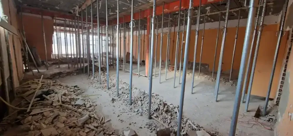 Sitio de construcción con trabajadores, estructura de madera y cimentación del edificio.