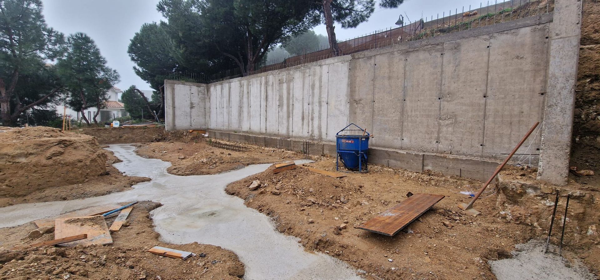 Sitio de construcción con muro de hormigón, tierra y caminos de hormigón húmedo.